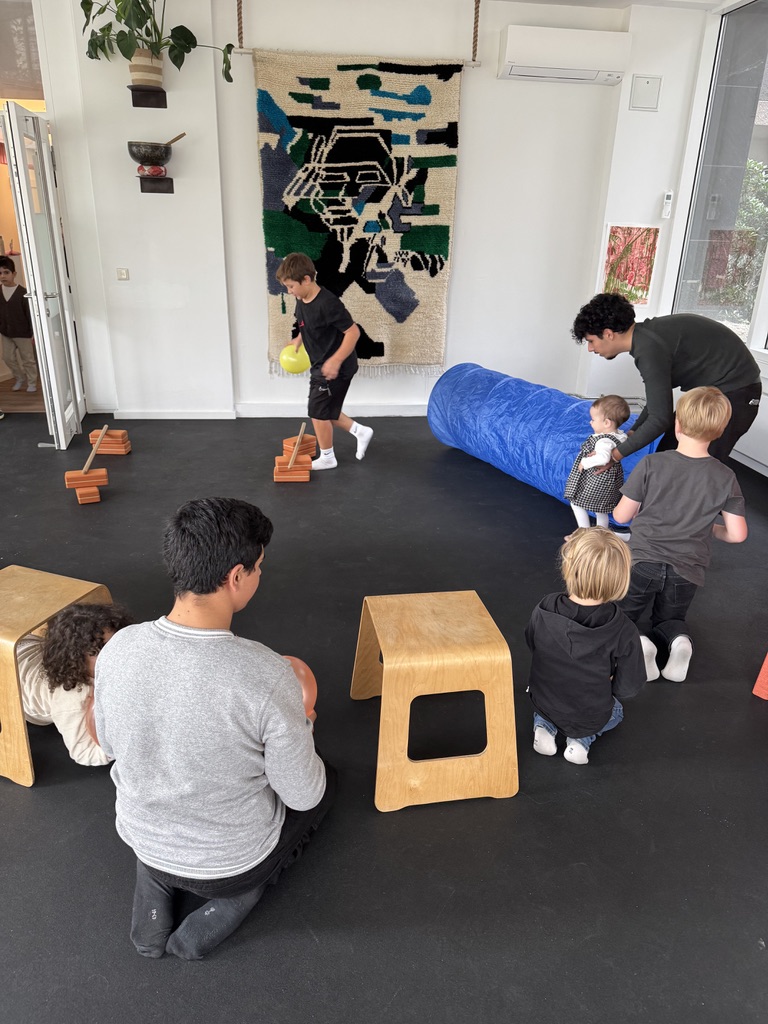 Kinder und Eltern beim aktiven Kinderkurs mit Kletterhocker und Turnrolle im Kursraum von Fit durch Physio am Bayerischen Platz in Berlin-Schöneberg.