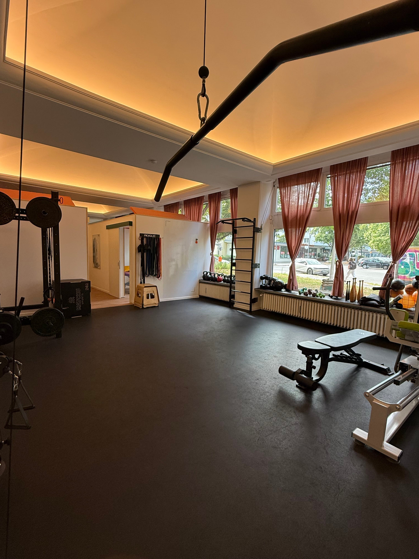 Helle, geräumige Trainingsfläche von Fit durch Physio mit Kabelzug, Hanteln, Sprossenwand und Bank – ideale Umgebung für evidenzbasierte Gerätegestützte Physiotherapie und Personal Training in Berlin-Schöneberg.