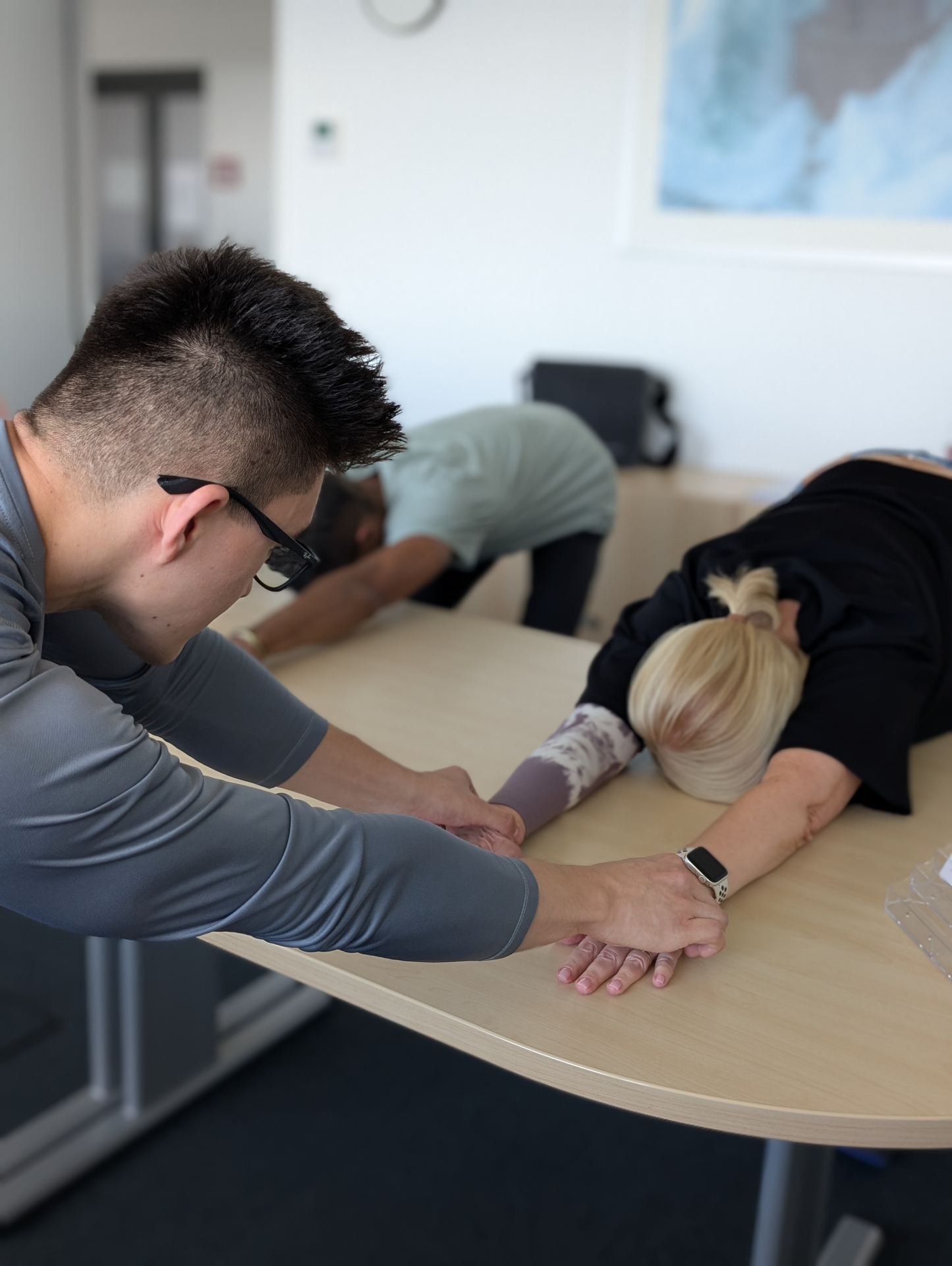 Physiotherapeutin begleitet zwei Patient:innen bei einer gerätegestützten Dehnungsübung im BGM-Kontext – Betriebliches Gesundheitsmanagement bei Fit durch Physio in Berlin.